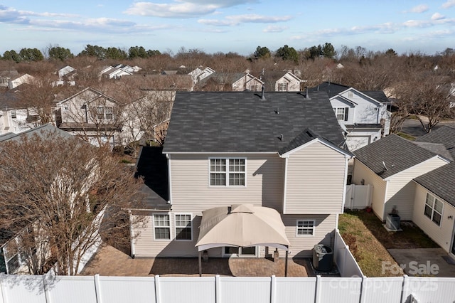 rear view of house featuring central air condition unit, a residential view, a fenced backyard, and roof with shingles