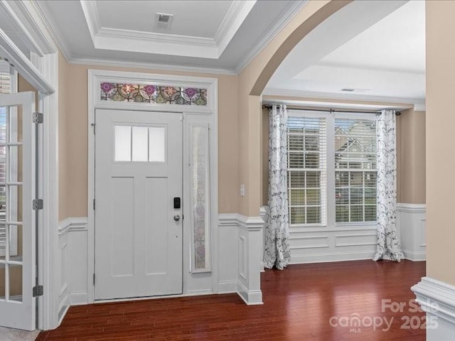 foyer featuring crown molding, dark hardwood / wood-style floors, and a raised ceiling