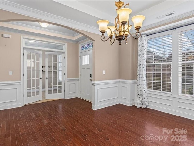 unfurnished dining area with an inviting chandelier, dark wood-type flooring, and ornamental molding