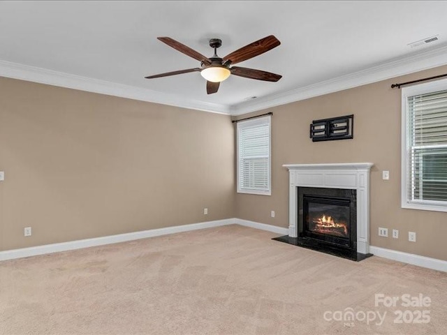 unfurnished living room featuring crown molding, ceiling fan, a high end fireplace, and light carpet