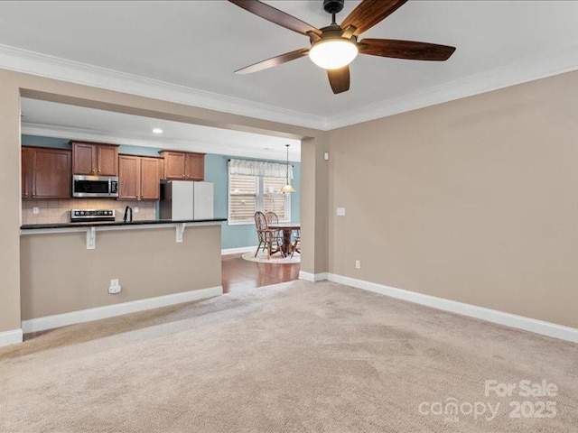 kitchen featuring a breakfast bar area, decorative light fixtures, ornamental molding, white fridge, and light colored carpet