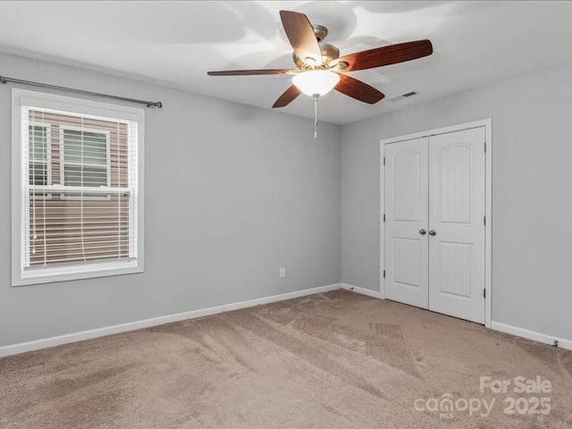 unfurnished bedroom with ceiling fan, light colored carpet, and a closet