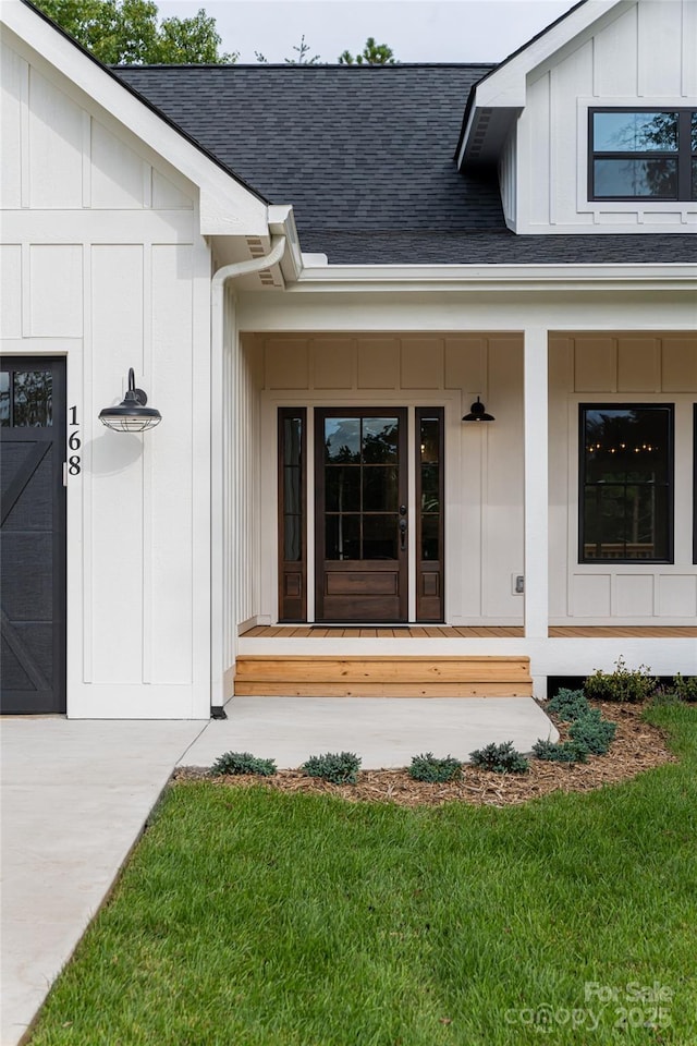 view of exterior entry featuring board and batten siding, roof with shingles, covered porch, and an attached garage