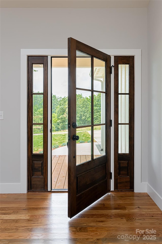 doorway featuring french doors, baseboards, and wood finished floors
