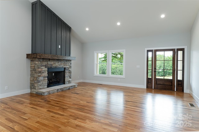 unfurnished living room with light wood finished floors, visible vents, baseboards, a stone fireplace, and recessed lighting