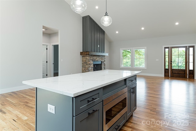 kitchen featuring stainless steel microwave, open floor plan, gray cabinets, and light wood finished floors