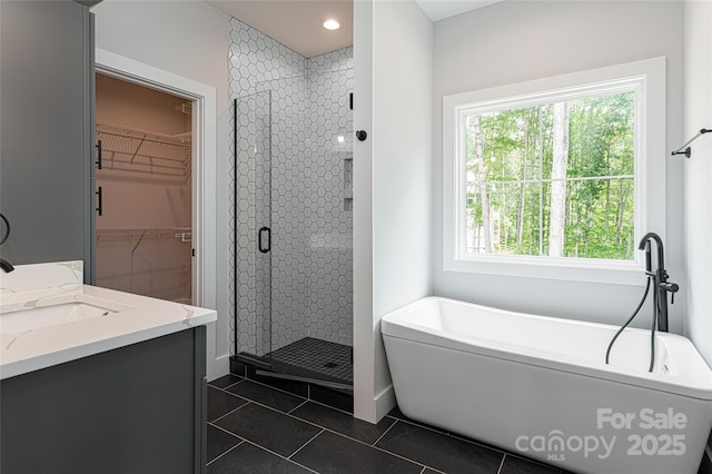 bathroom with tile patterned floors, a freestanding tub, a shower stall, a spacious closet, and vanity