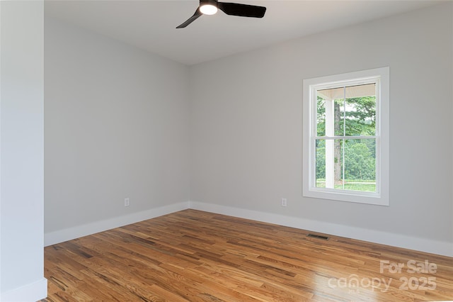 empty room featuring visible vents, baseboards, wood finished floors, and a ceiling fan