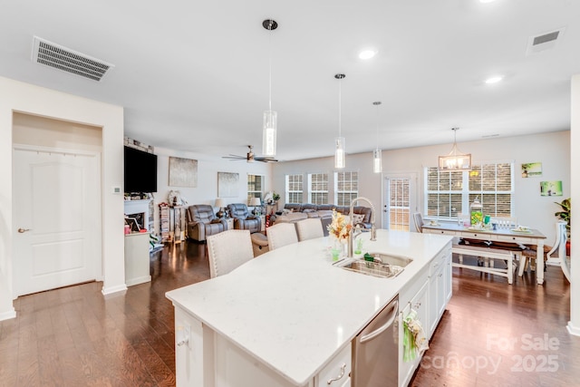 kitchen featuring pendant lighting, sink, white cabinets, dark hardwood / wood-style flooring, and a kitchen island with sink