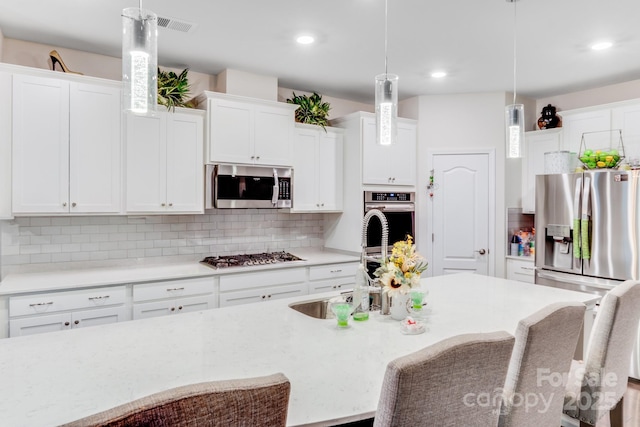 kitchen featuring white cabinetry, decorative light fixtures, and appliances with stainless steel finishes