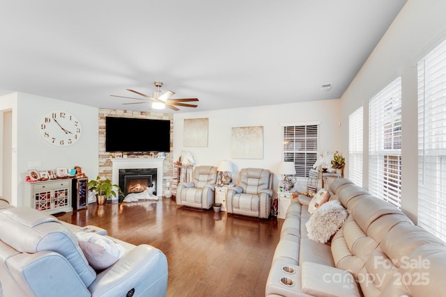 living room featuring ceiling fan, dark hardwood / wood-style floors, and a fireplace