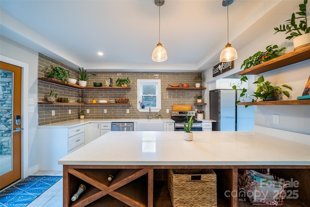 kitchen featuring pendant lighting, sink, white cabinetry, backsplash, and stainless steel appliances