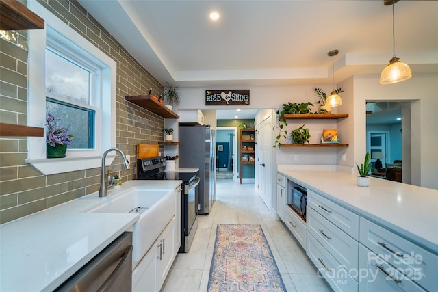 kitchen with sink, appliances with stainless steel finishes, hanging light fixtures, backsplash, and white cabinets