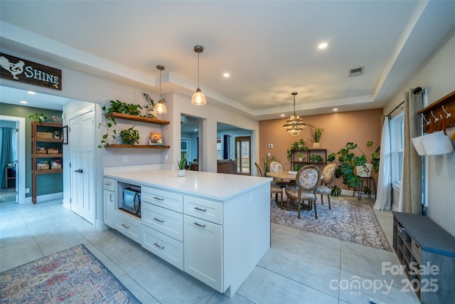 kitchen featuring light tile patterned floors, white cabinetry, hanging light fixtures, kitchen peninsula, and a raised ceiling