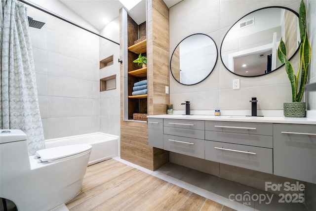 full bathroom with shower / tub combo with curtain, tile walls, vanity, wood-type flooring, and toilet