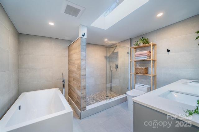 full bathroom with tile walls, a skylight, shower with separate bathtub, and toilet