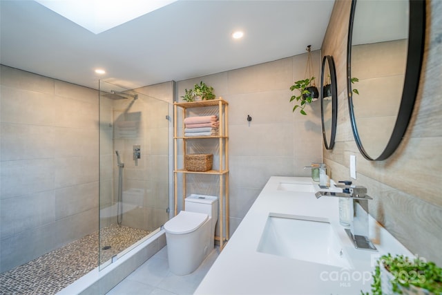 bathroom featuring tile walls, tile patterned flooring, tiled shower, vanity, and toilet