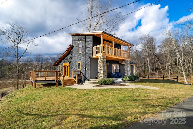 view of front of property featuring a wooden deck, a balcony, and a front yard