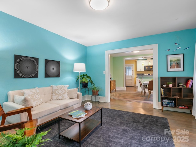 living area with baseboards and wood finished floors