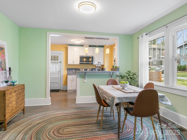 dining area with baseboards and wood finished floors