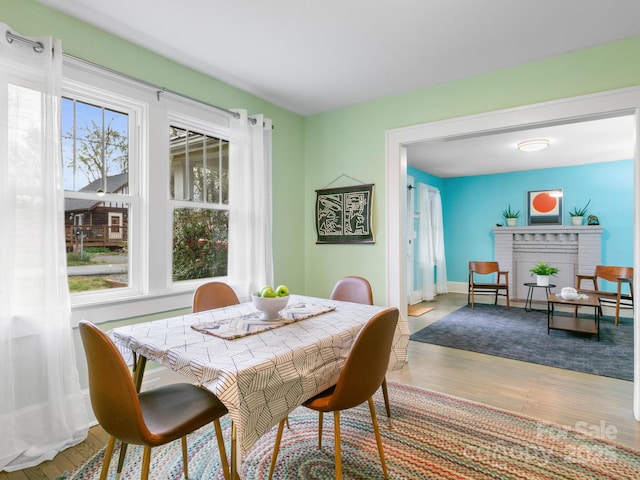 dining space featuring baseboards, a fireplace, and wood finished floors