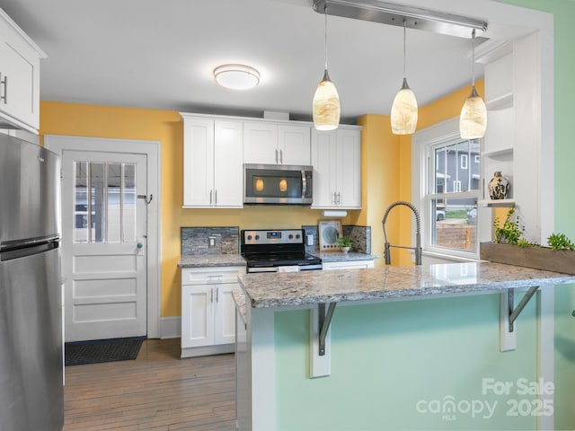 kitchen featuring a kitchen breakfast bar, a sink, stainless steel appliances, and white cabinetry