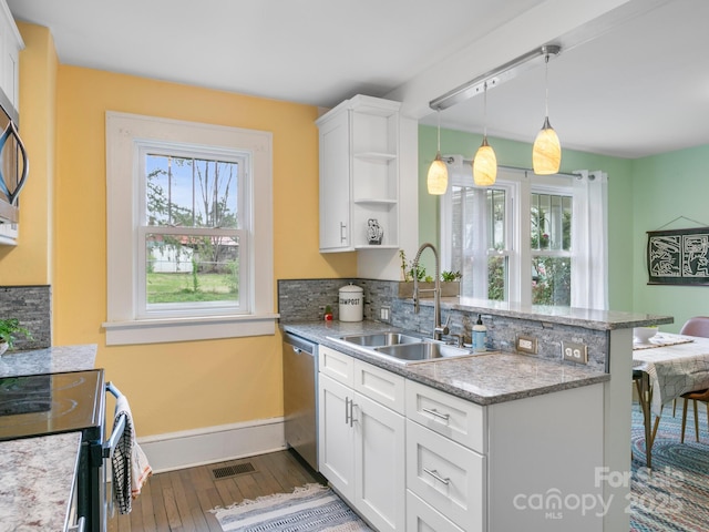 kitchen featuring visible vents, a peninsula, appliances with stainless steel finishes, a sink, and open shelves