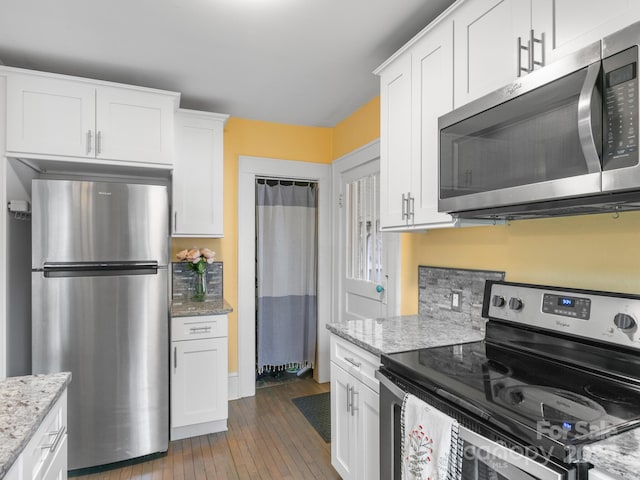 kitchen with wood-type flooring, white cabinets, light stone countertops, and stainless steel appliances