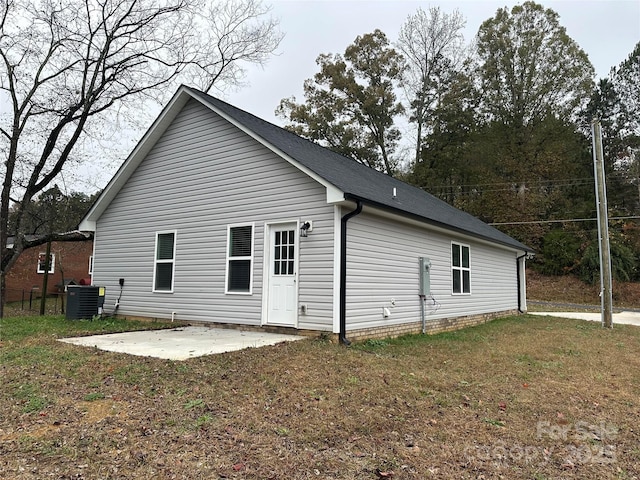 rear view of property featuring a lawn, cooling unit, and a patio area