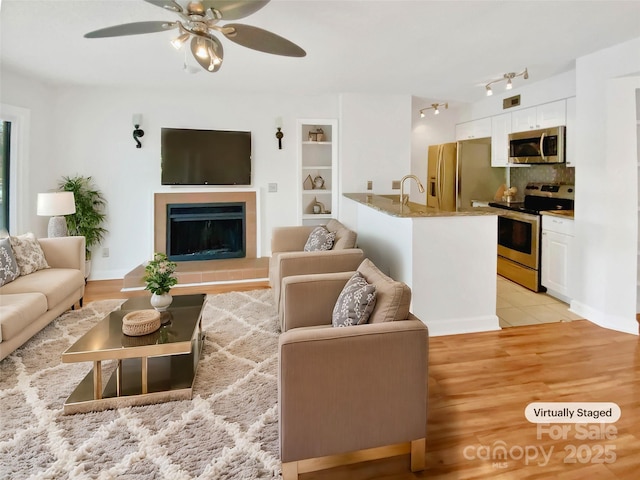 living room featuring rail lighting, ceiling fan, and light hardwood / wood-style flooring