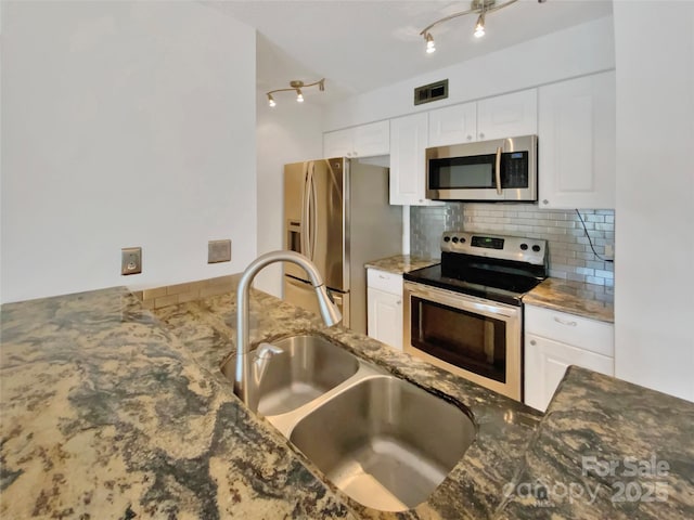 kitchen featuring sink, stainless steel appliances, dark stone counters, and white cabinets