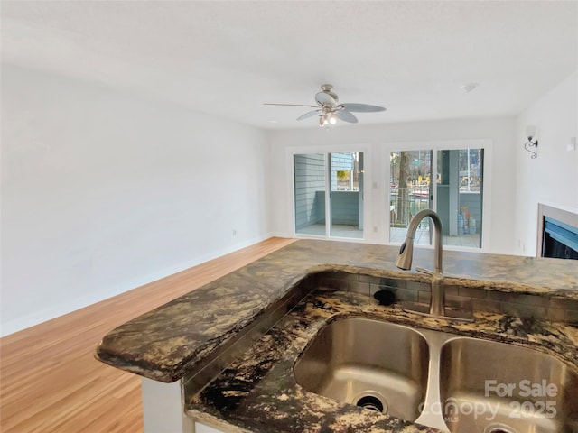 kitchen with ceiling fan, kitchen peninsula, sink, and hardwood / wood-style floors