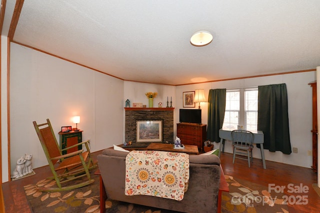 living room with crown molding, a stone fireplace, and wood-type flooring