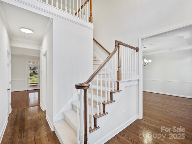 stairs featuring wood-type flooring, a chandelier, and crown molding