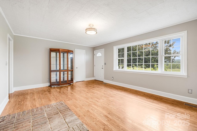 foyer featuring ornamental molding, light hardwood / wood-style floors, and a textured ceiling