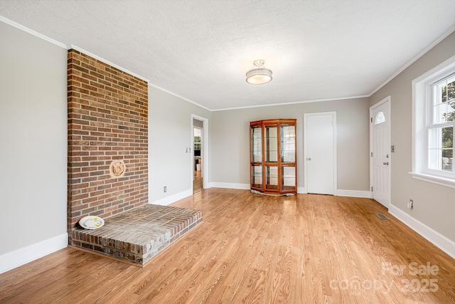 unfurnished living room featuring ornamental molding, a textured ceiling, and light hardwood / wood-style flooring