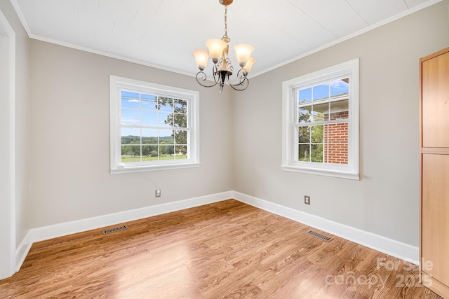 spare room featuring crown molding, hardwood / wood-style floors, and a chandelier