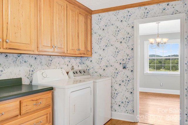 laundry area with crown molding, an inviting chandelier, cabinets, wood-type flooring, and washer and dryer