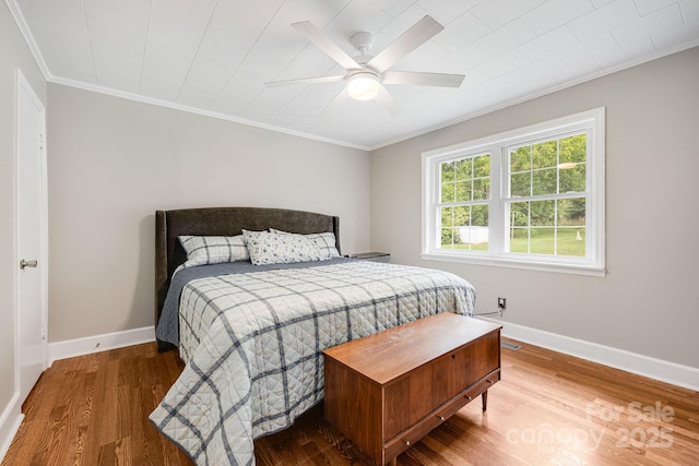 bedroom with hardwood / wood-style flooring, ornamental molding, and ceiling fan