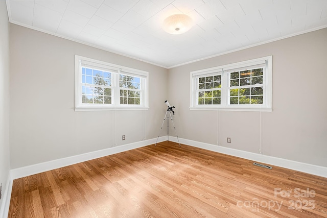 spare room featuring plenty of natural light, ornamental molding, and wood-type flooring