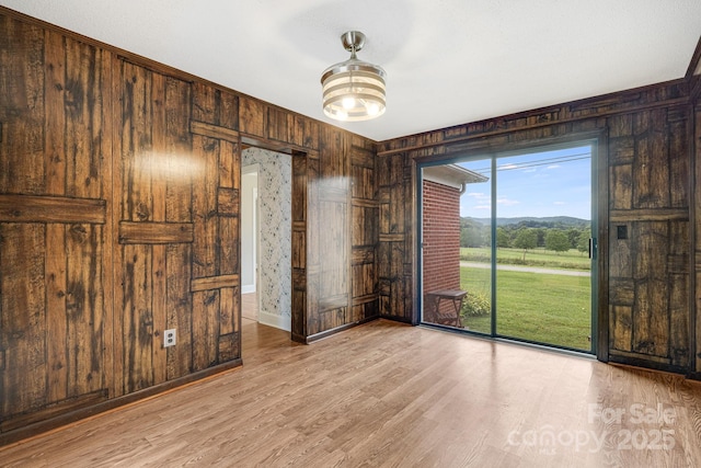 spare room with wooden walls and light wood-type flooring