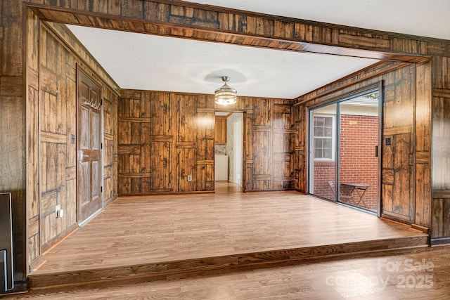 spare room featuring wood-type flooring, washer / dryer, and wood walls