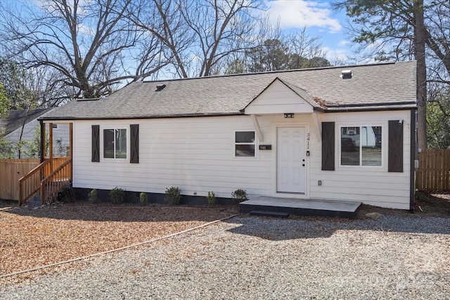 view of front facade featuring roof with shingles and fence