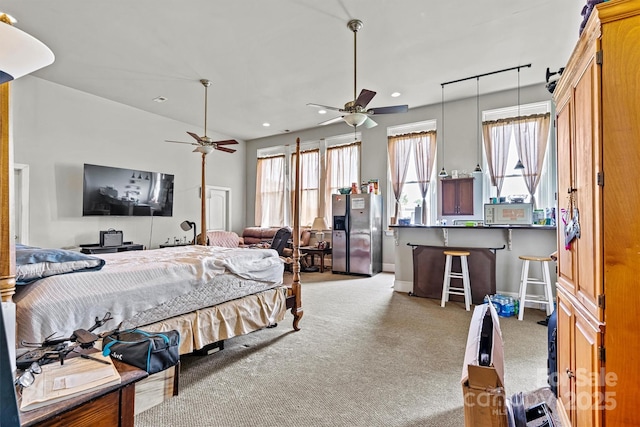 bedroom with stainless steel refrigerator with ice dispenser, light colored carpet, and ceiling fan