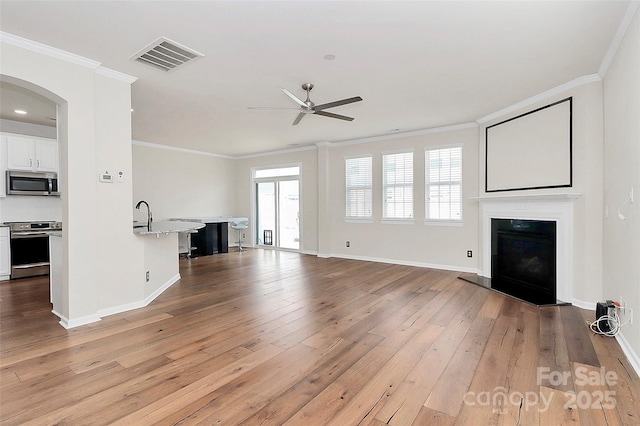 unfurnished living room with ceiling fan, crown molding, light hardwood / wood-style flooring, and a healthy amount of sunlight