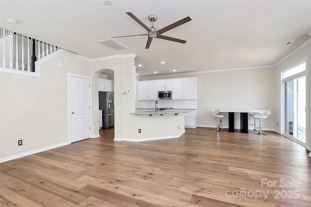 unfurnished living room featuring ornamental molding, sink, ceiling fan, and light hardwood / wood-style floors