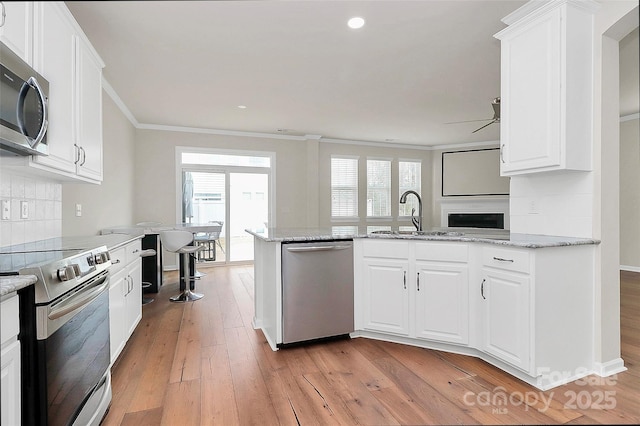 kitchen with sink, appliances with stainless steel finishes, white cabinetry, tasteful backsplash, and light stone countertops