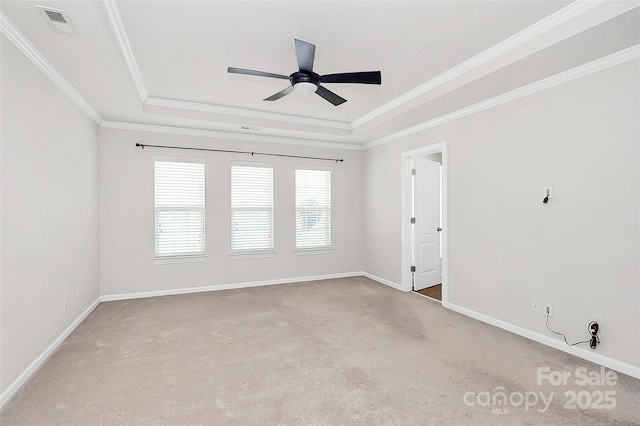 carpeted spare room featuring crown molding, a tray ceiling, and ceiling fan