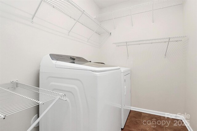 clothes washing area with separate washer and dryer and dark tile patterned floors