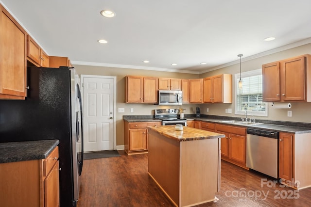 kitchen featuring sink, dark wood-type flooring, stainless steel appliances, a center island, and decorative light fixtures